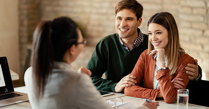 Couple smiling in office during a mortgage consultation.